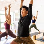 Diverse group of students doing crescent lunge pose during yoga class